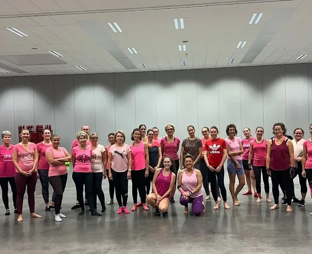 Octobre rose : un grand groupe vêtu de rose aligné dans un gymnase