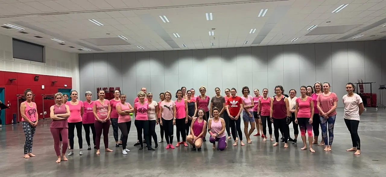 Octobre rose : un grand groupe vêtu de rose aligné dans un gymnase