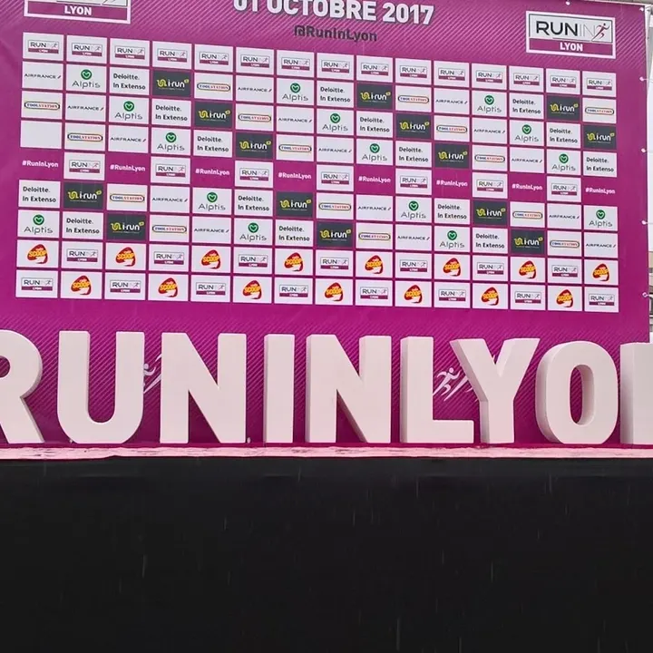 Lettres géantes « RUN IN LYON » devant le panneau d’une course à pied