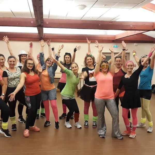 Groupe en tenues fluo des années 80, jambières et bandeaux, bras levés
