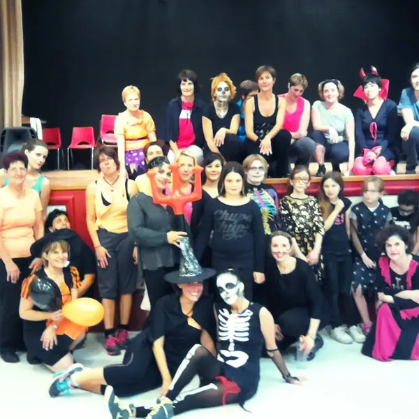 Photo de groupe costumée pour Halloween devant une scène : squelettes, sorcières et cornes de diable