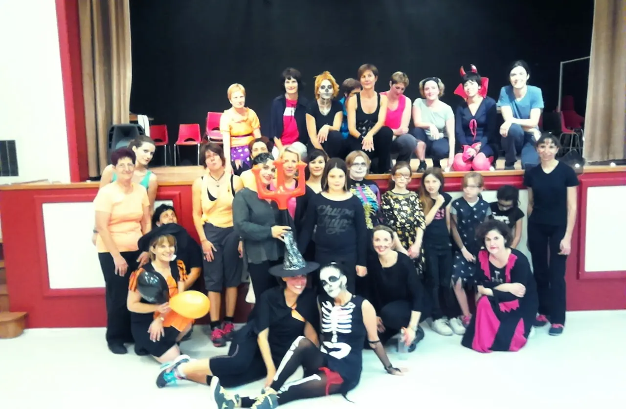 Photo de groupe costumée pour Halloween devant une scène : squelettes, sorcières et cornes de diable
