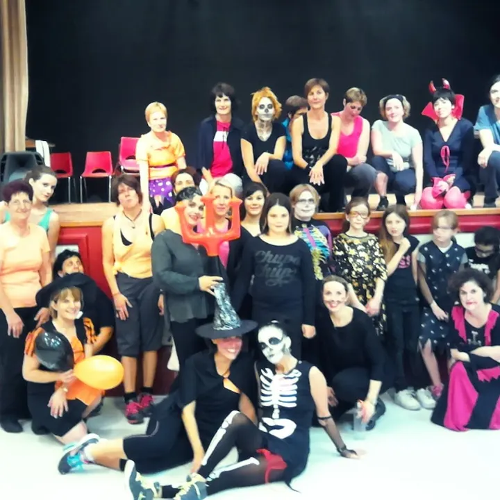 Photo de groupe costumée pour Halloween devant une scène : squelettes, sorcières et cornes de diable