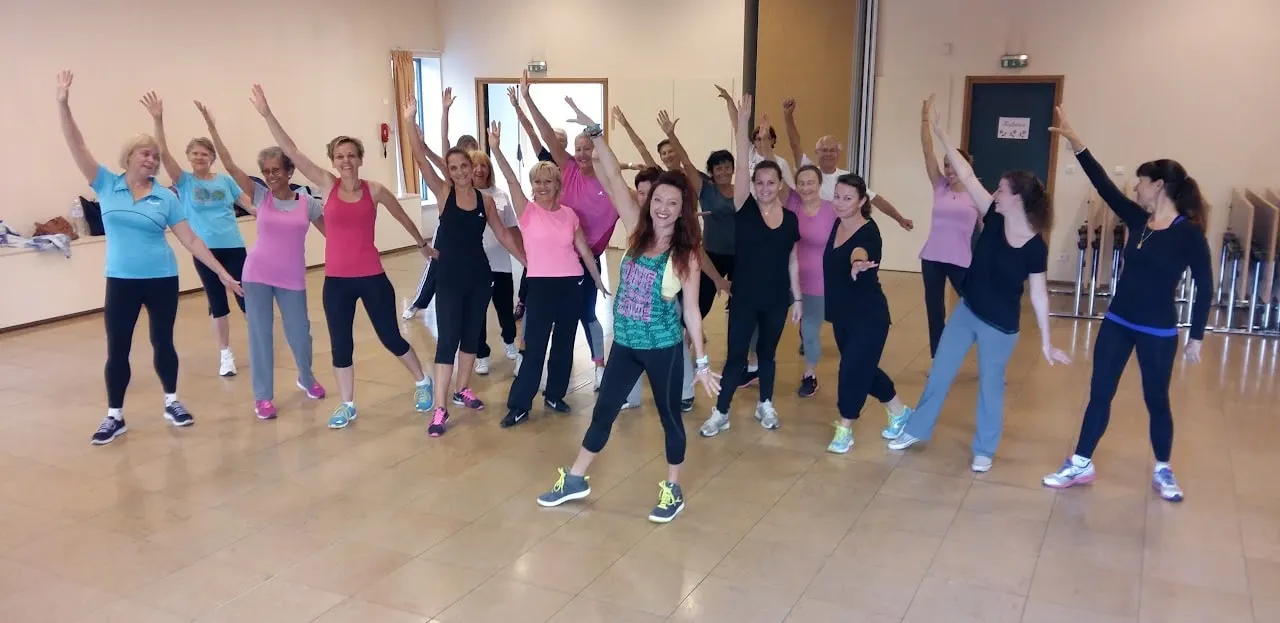 Un groupe en pleine chorégraphie, bras levés, dans une salle au sol carrelé