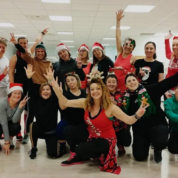 Groupe en bonnets de Père Noël et serre-têtes de renne, bras écartés, tout sourire