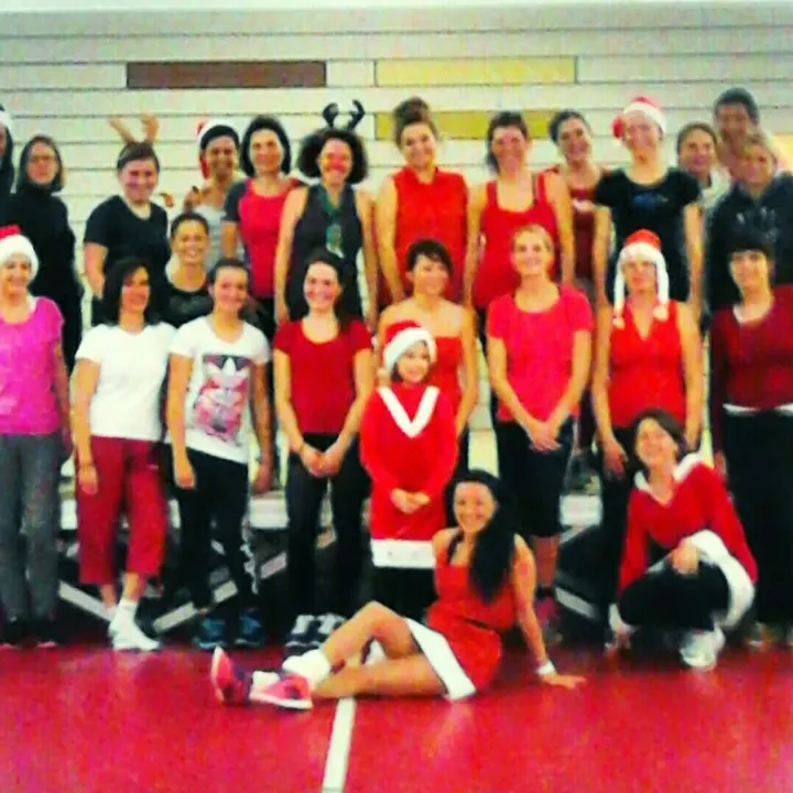 Grand groupe en rouge et blanc, bonnets de Père Noël, posant dans un gymnase